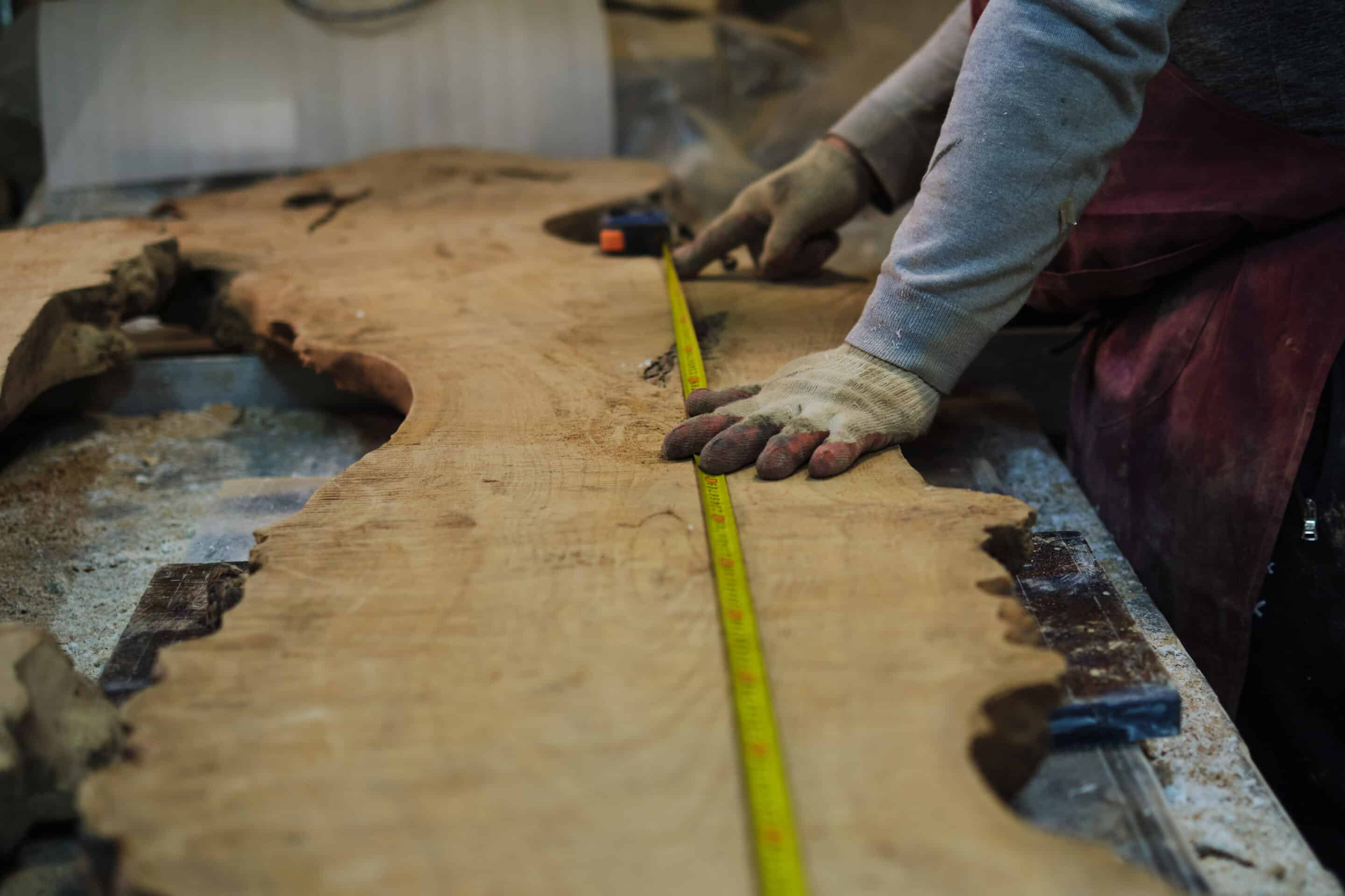 Craftsman marks wood with a ruler and pencil. Precision in handcraft aligns with the bespoke furniture trend